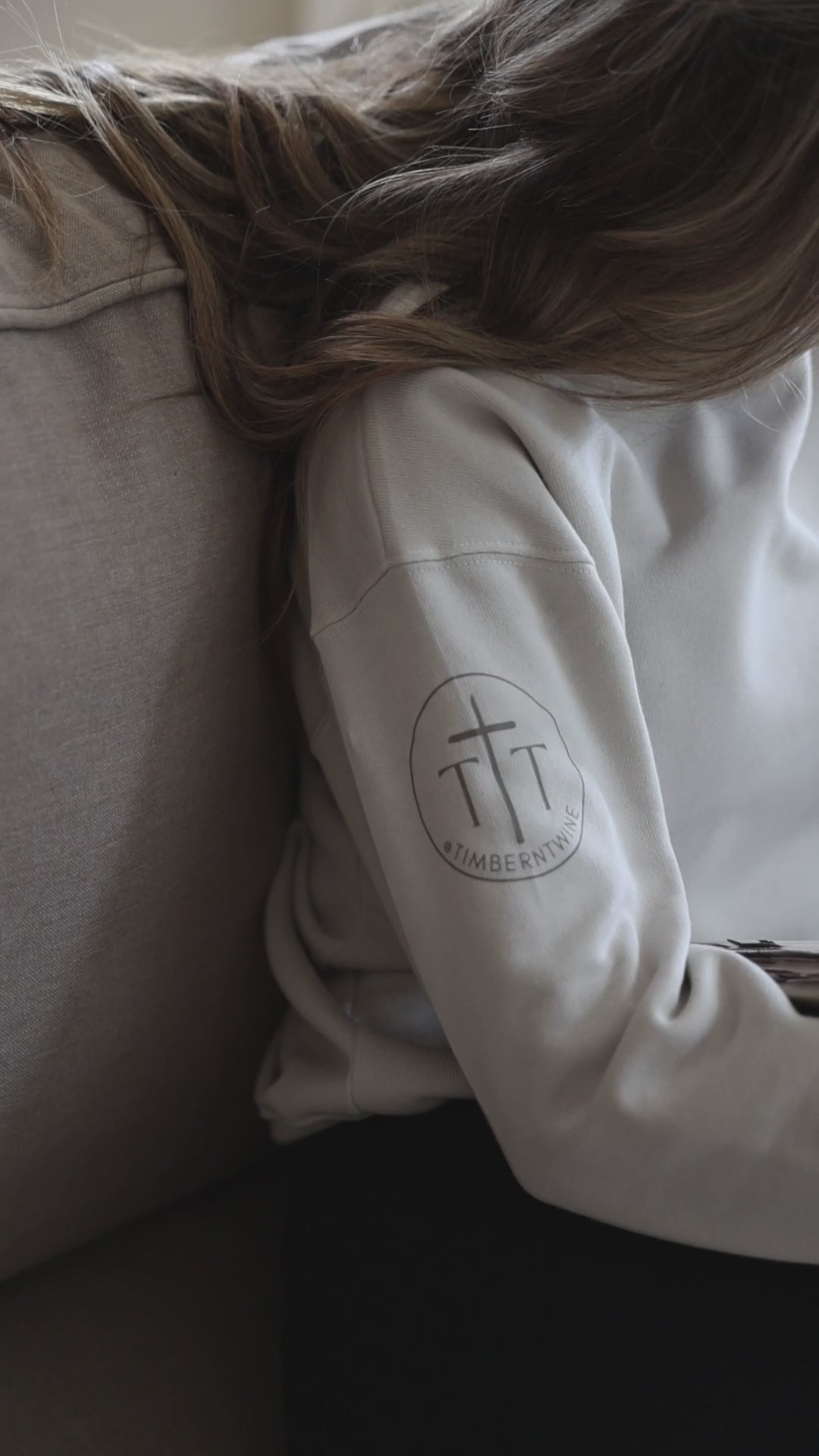 woman sitting on a couch reading a book while wearing a sweatshirt